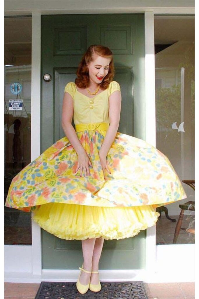 Model wearing yellow 50s style sundress with thin straps and full skirt