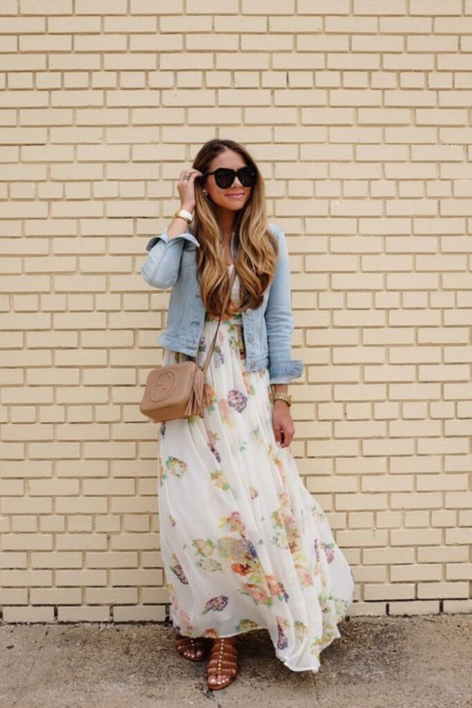 woman in floral maxi dress, jean jacket, circle sunnies, shoulder bag, and flat sandals