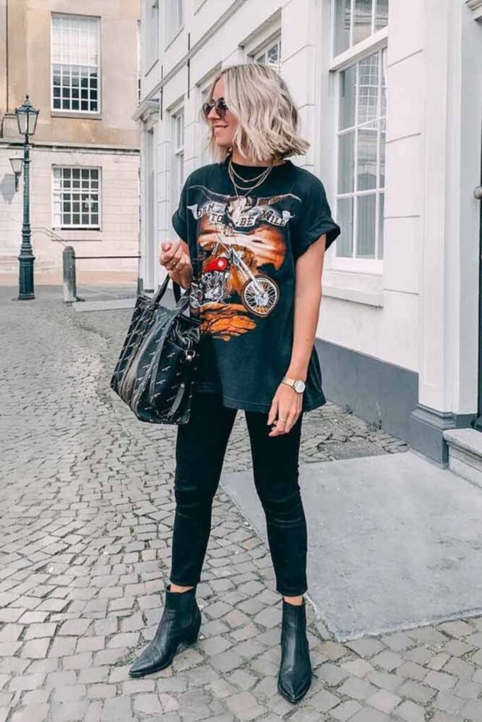 woman in graphic band tee, ripped black jeans, and black combat boots