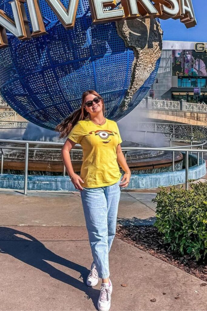 women wearing a Minions graphic tee, light blue jeans, and white converse sneakers