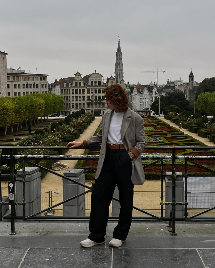 Taupe oversized blazer with a white tee, black trousers and white sneakers overlooking Brussels