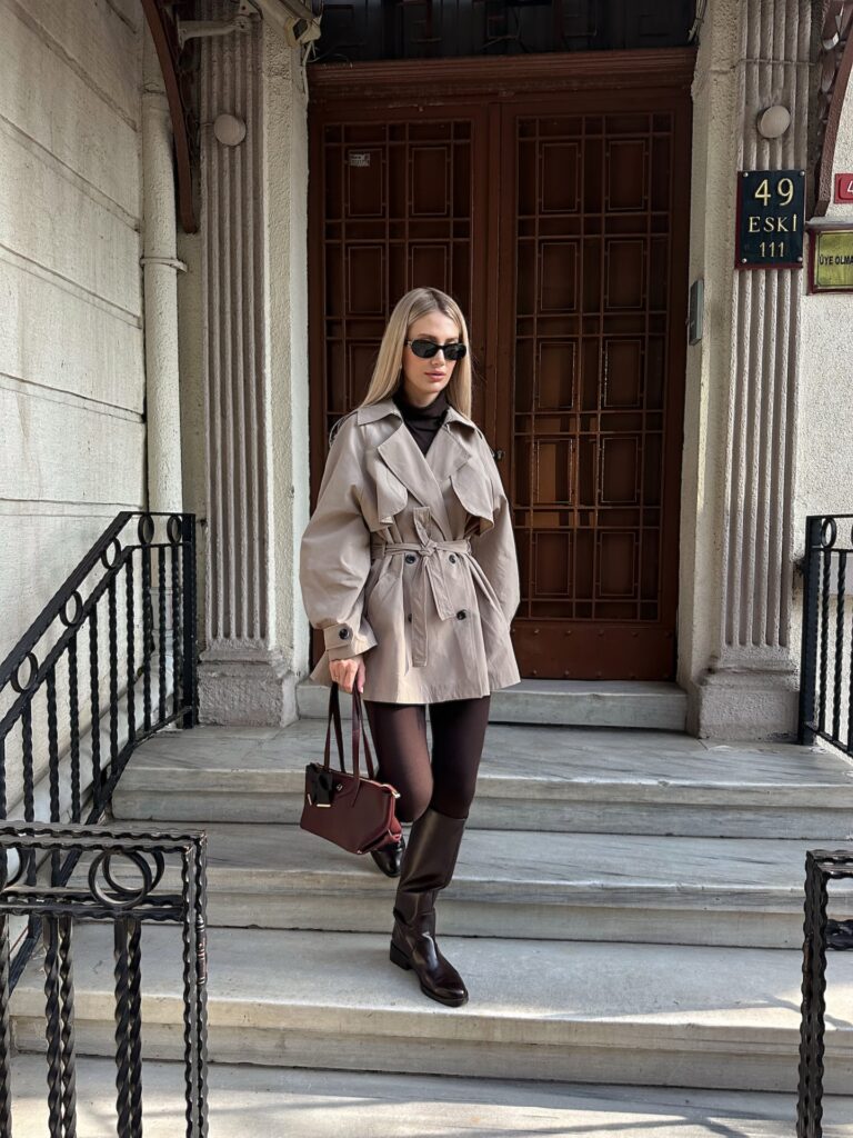 Taupe belted short trench coat with a brown turtleneck, brown tights and brown knee-high boots
