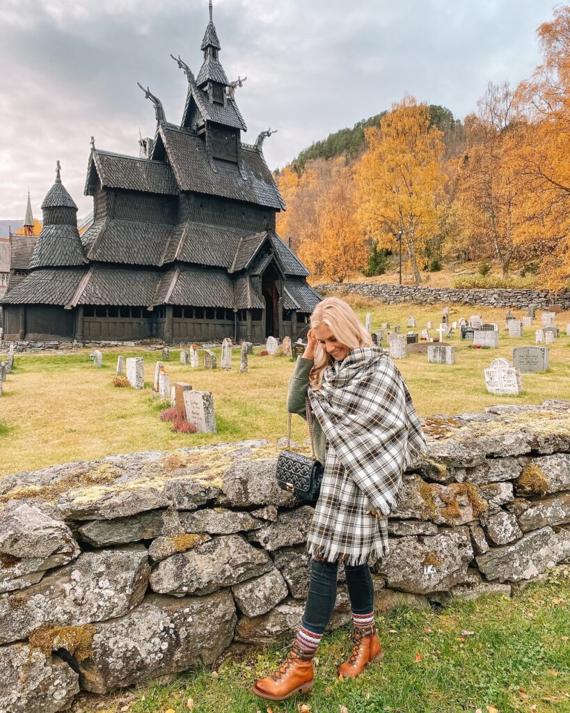 Olive knit sweater with an oversized plaid blanket scarf, jeans, lace-up hiking boots and Fair Isle socks in Norway