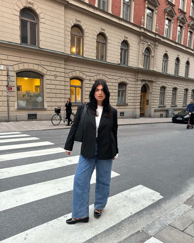 Black blazer over a white top with blue straight-leg jeans and black ballet flats