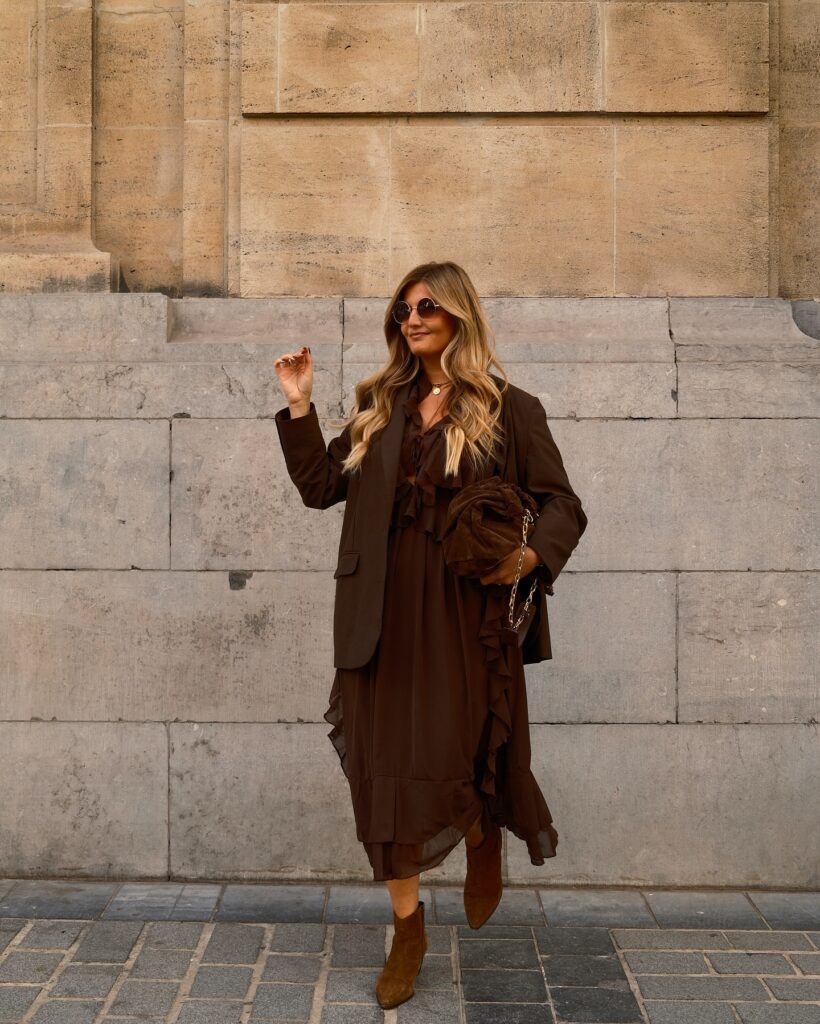 Brown ruffled chiffon midi dress layered under a dark brown oversized blazer with brown suede ankle boots