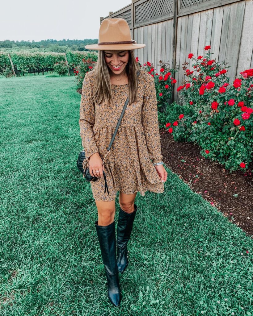 Woman in a mustard floral long-sleeve mini dress, camel felt hat and black knee boots