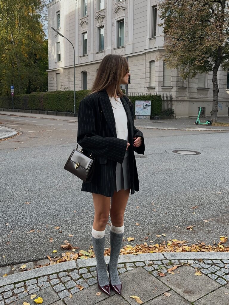 Oversized pinstripe blazer with a grey pleated mini skirt, grey knee-high socks and burgundy heels