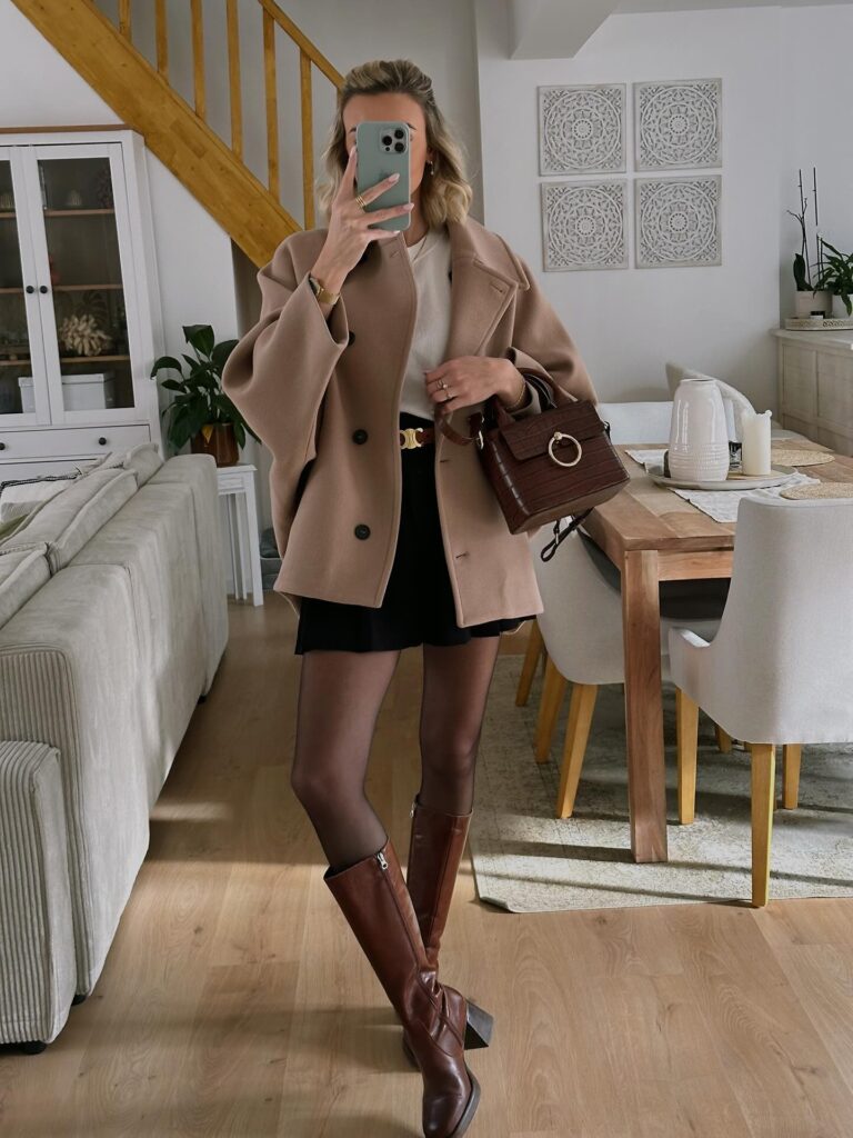 Camel pea coat over a cream top and black mini skirt with sheer tights and tall brown leather boots