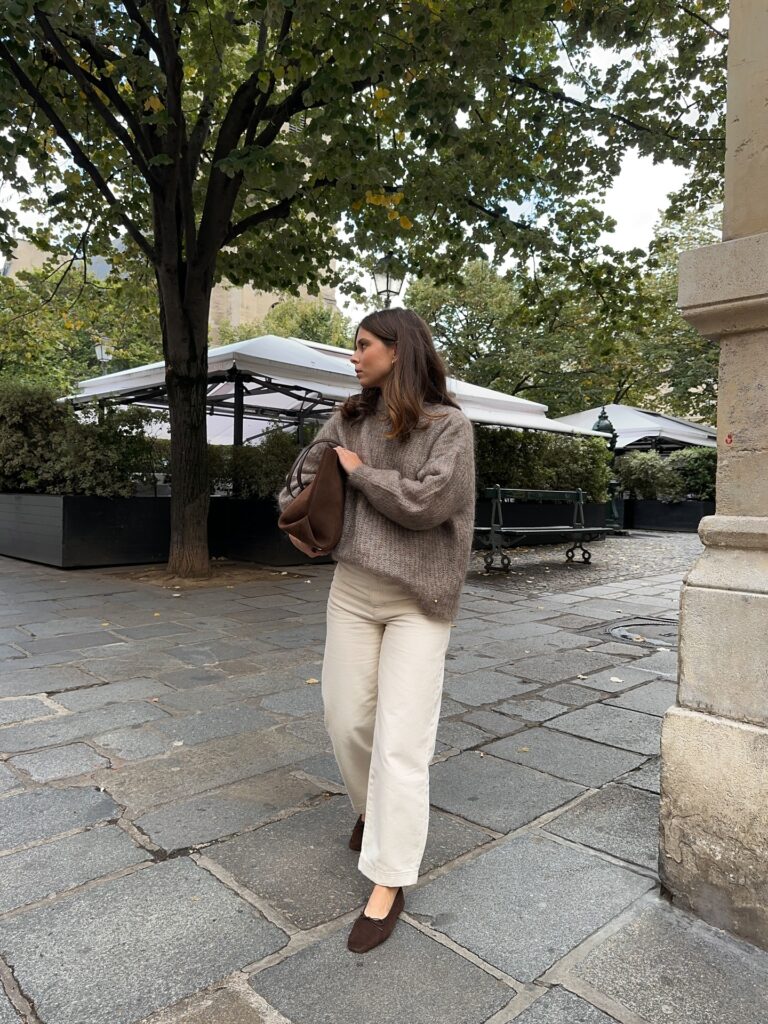 Woman in a soft mushroom-toned mohair jumper with cream wide-leg jeans and brown ballet flats at a Paris café