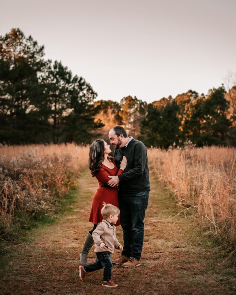 Couple and toddler in a golden field, mom in red dress