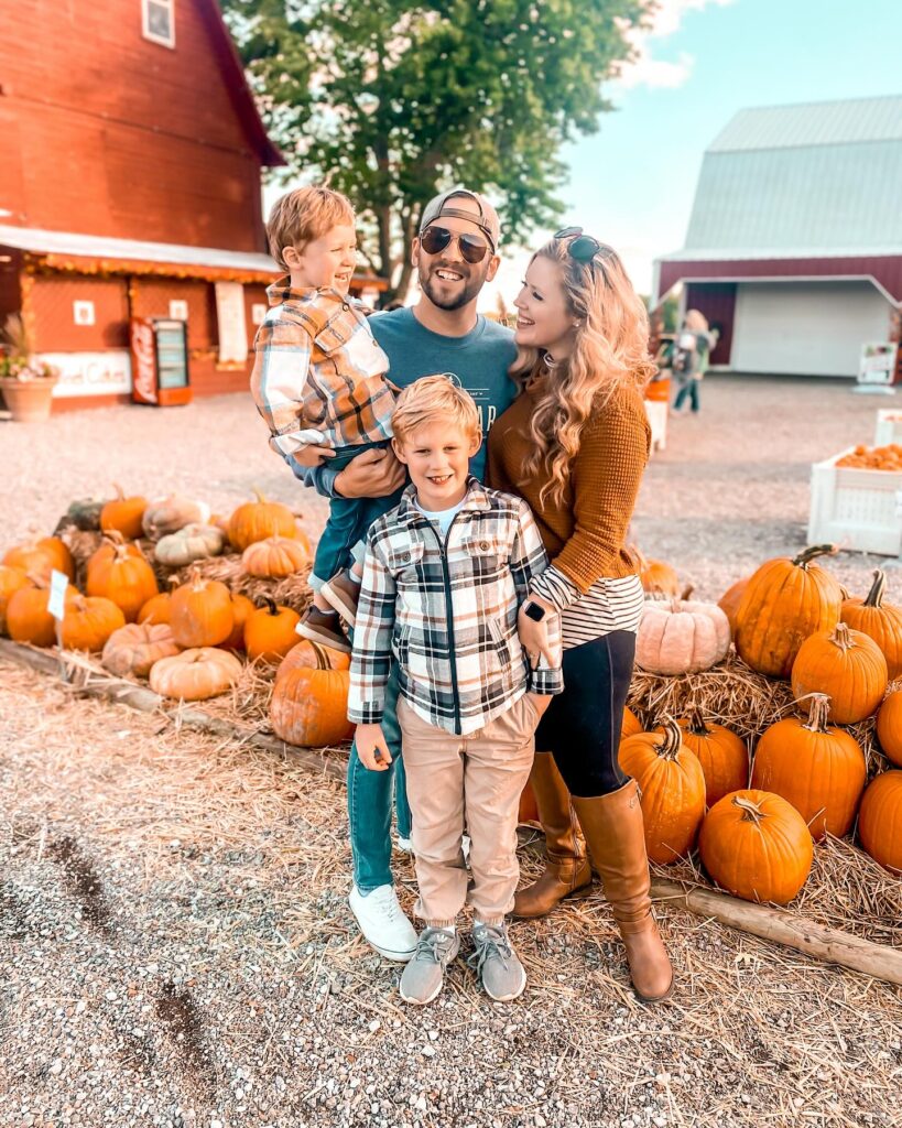 Family at a pumpkin patch in plaid and rust