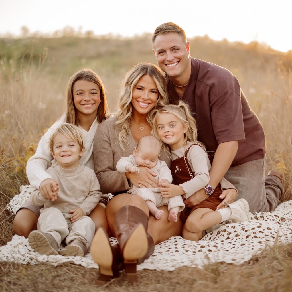 Family of six sitting in a golden grass field in warm browns