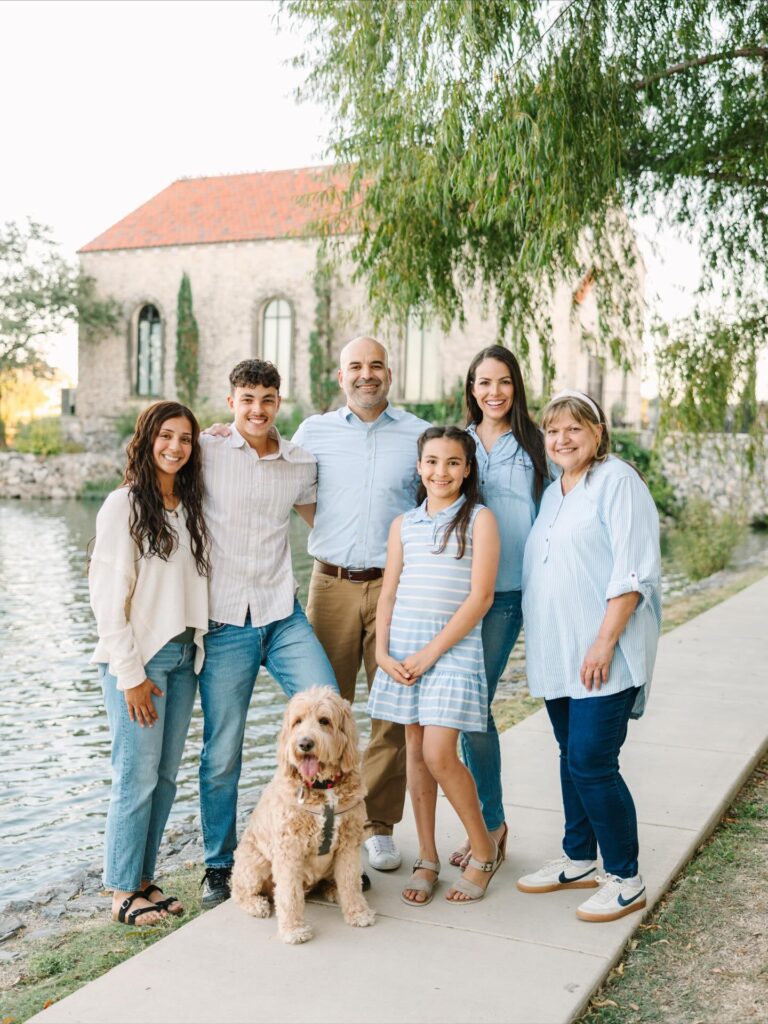 Three generations plus a dog by a pond, shades of blue chambray