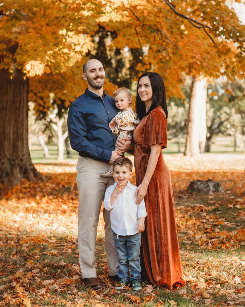 Family under an orange tree, mom in rust velvet dress