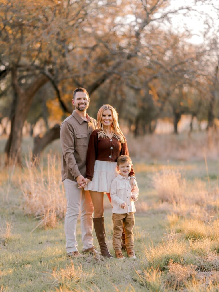 Family of three in a pecan orchard, mom in maroon and tall boots