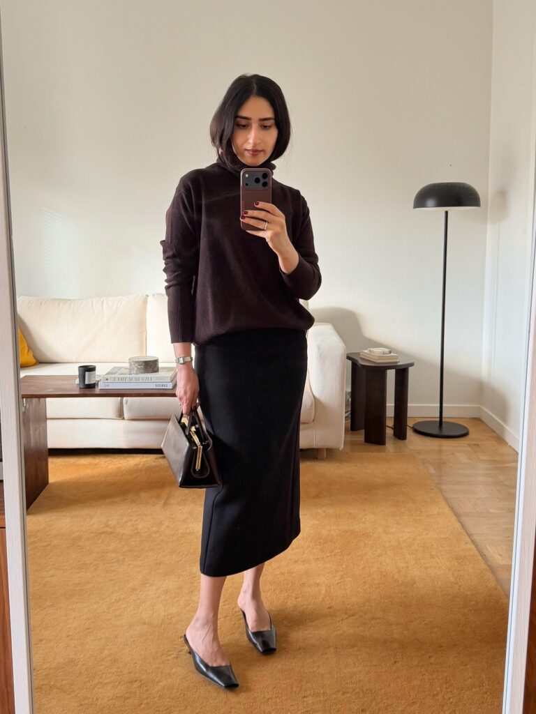 Mirror selfie of a woman wearing a dark brown turtleneck sweater tucked into a black midi pencil skirt with black kitten heel mules and a small structured bag