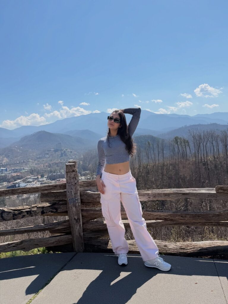 Woman wearing a striped long-sleeve crop top, pale pink cargo pants, and New Balance sneakers at a Gatlinburg mountain overlook